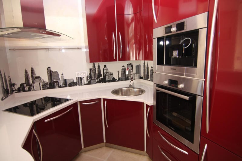 Cuisine rouge moderne avec électroménager Bosch et crédence imprimée d’une ville dans une villa à Lastva, Monténégro.