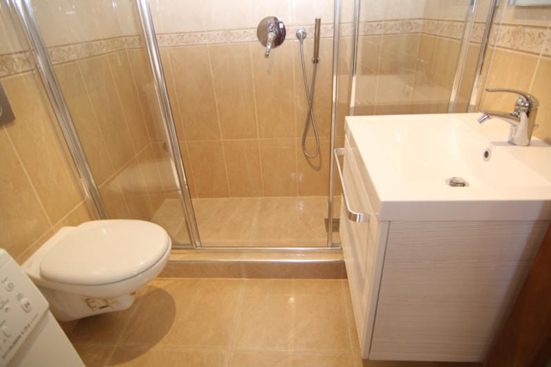 Salle de bains avec cabine de douche et mobilier clair dans une villa à Lastva, Monténégro : finition moderne en carrelage.