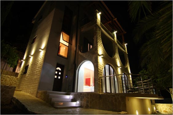Villa de trois étages à Lastva Grbaljska, Monténégro : éclairage nocturne de la façade, parement en pierre et terrasses en arcades.