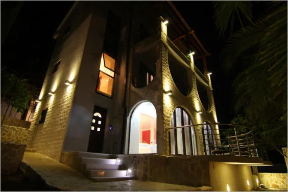 Villa de trois étages à Lastva Grbaljska, Monténégro : éclairage nocturne de la façade, parement en pierre et terrasses en arcades.