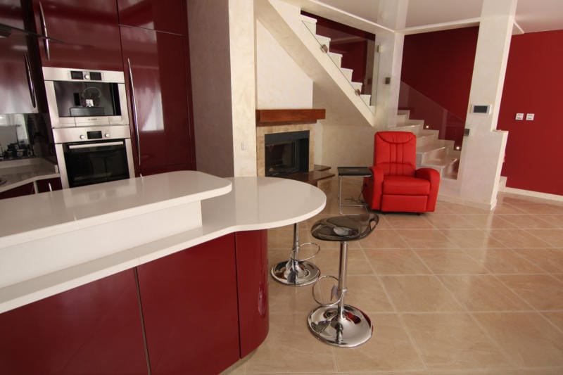 Cuisine moderne avec mobilier bordeaux, bar et cheminée dans une villa à Lastva, Monténégro.