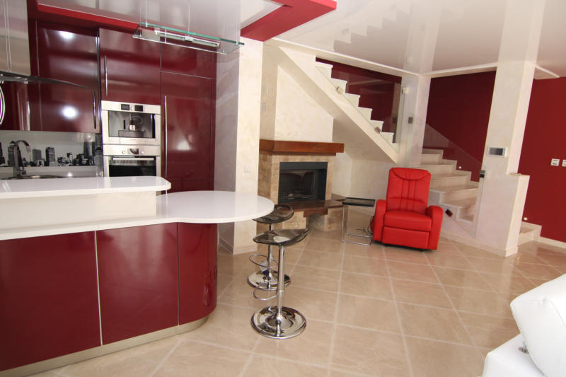 Cuisine-salon moderne avec bar et cheminée dans une villa à Lastva, Monténégro : intérieur élégant avec escalier.