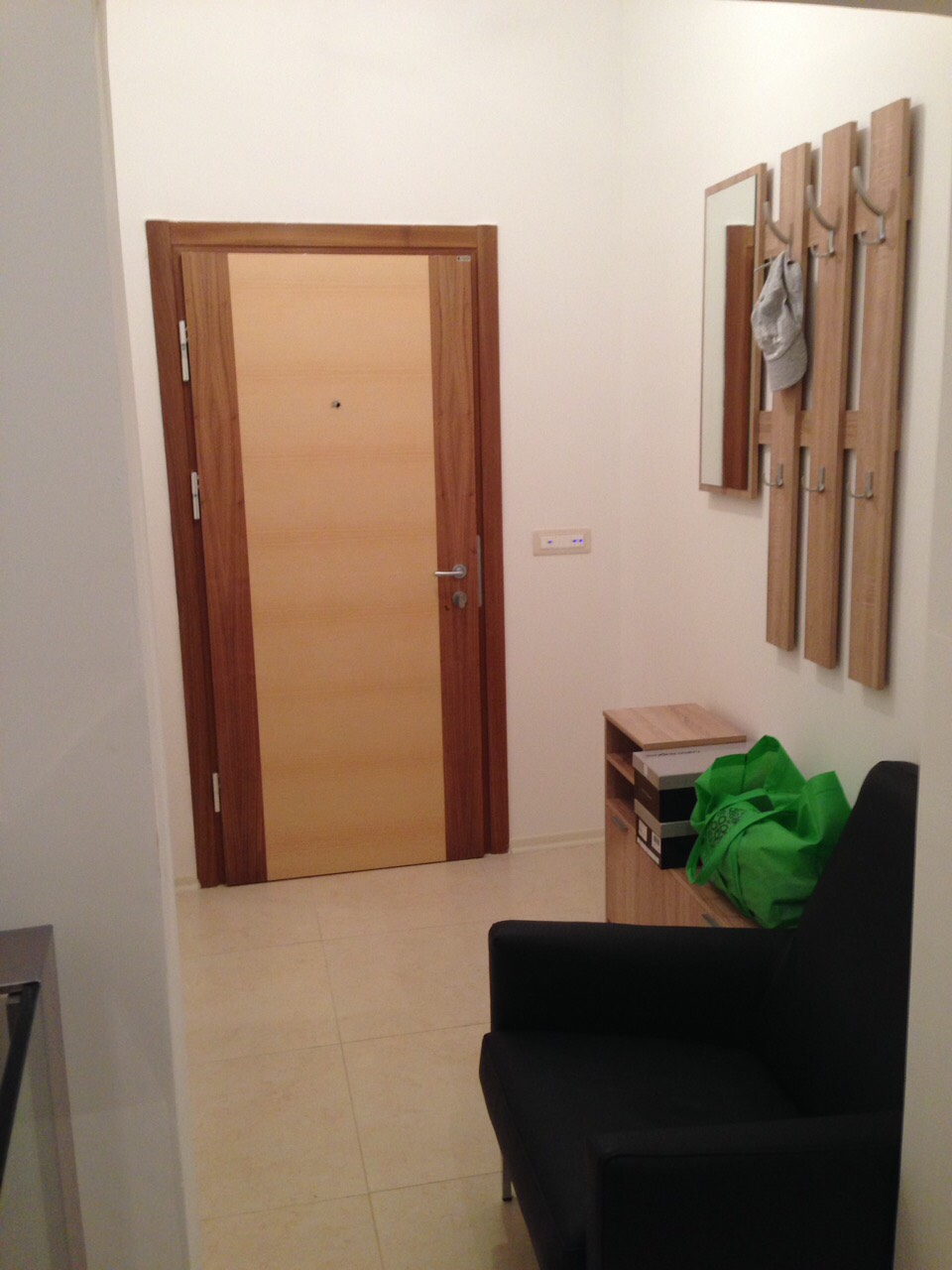 Flur in einer Wohnung in Bečići, Montenegro: helle Ausstattung, Holzeingangstür, Garderobe mit Spiegel und Sessel.
