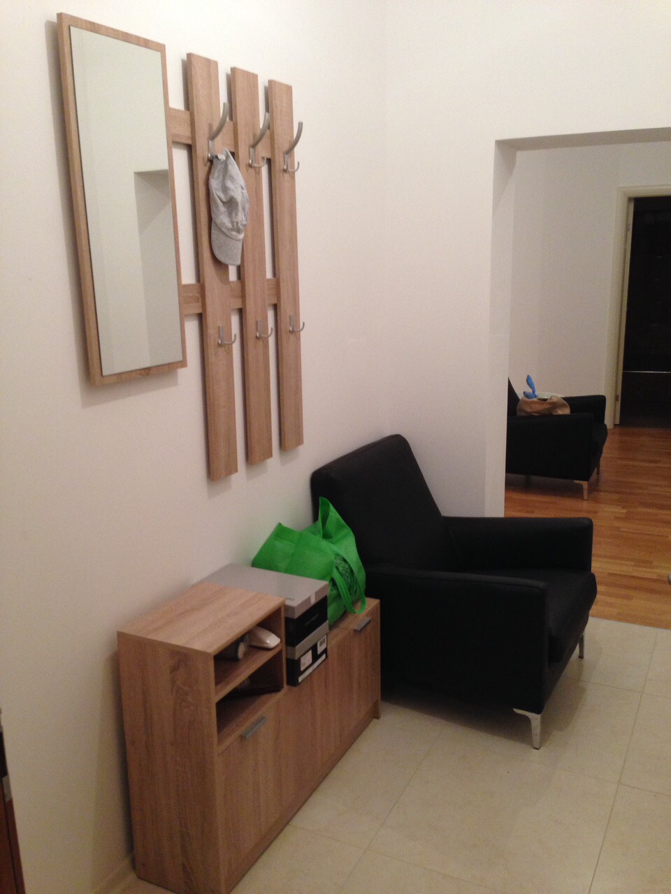 Flur in einer Wohnung in Bečići, Montenegro: Holz-Garderobe mit Spiegel, Schuhschrank und schwarzer Sessel.