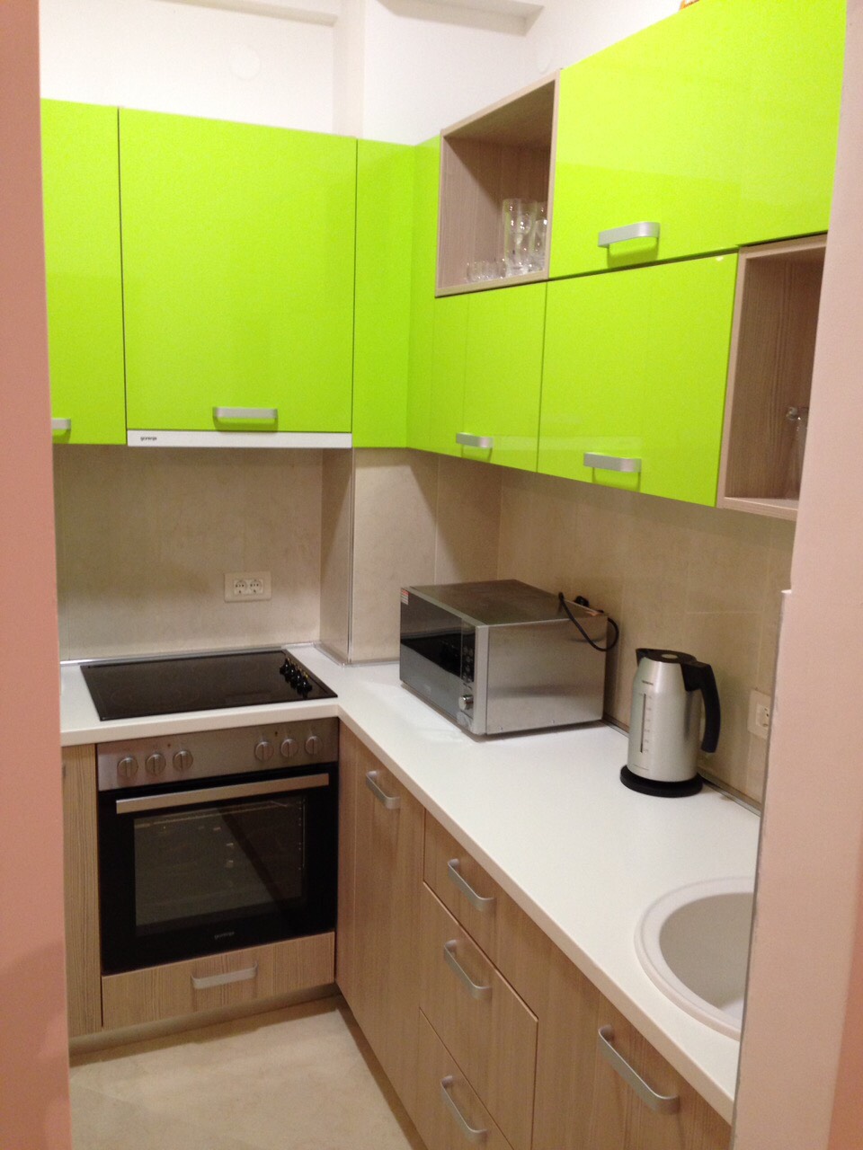 Moderne Küche mit leuchtend grünen Fronten in einer zum Verkauf stehenden Wohnung in Bečići, Montenegro: Einbaugeräte und Herd.