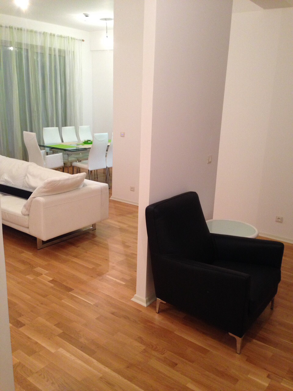 Modernes Wohnzimmer mit weißem Sofa und Essbereich in einer Wohnung in Bečići, Montenegro, Parkettboden und helles Interieur