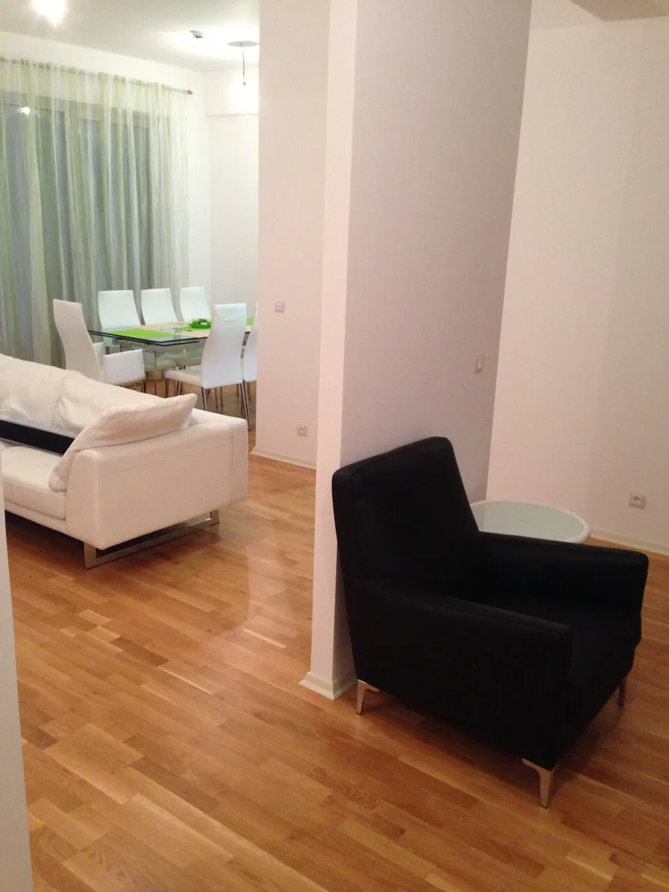 Modernes Wohnzimmer mit weißem Sofa und Essbereich in einer Wohnung in Bečići, Montenegro, Parkettboden und helles Interieur