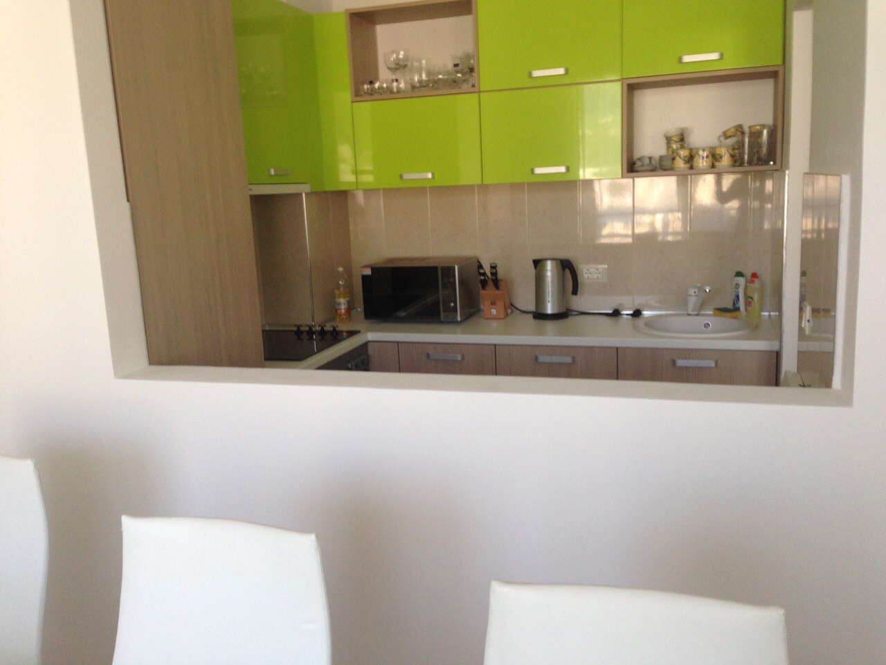 Moderne Küche mit leuchtend grünen Fronten in einer zum Verkauf stehenden Wohnung, Bečići, Montenegro: Blick auf den Arbeitsbereich und die Geräte.