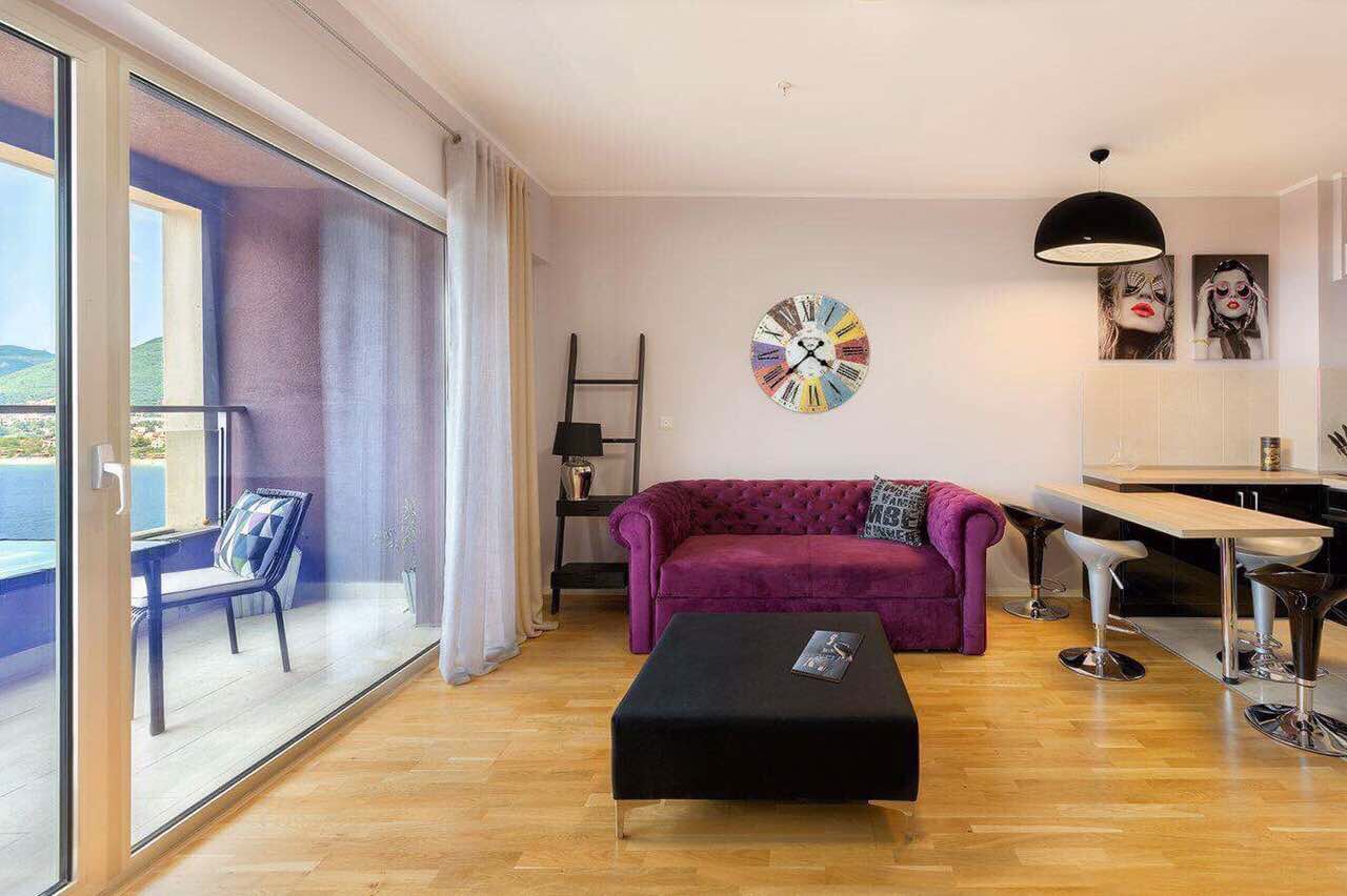 Salon avec canapé violet et vue panoramique sur la mer dans un appartement, Bečići, Monténégro.