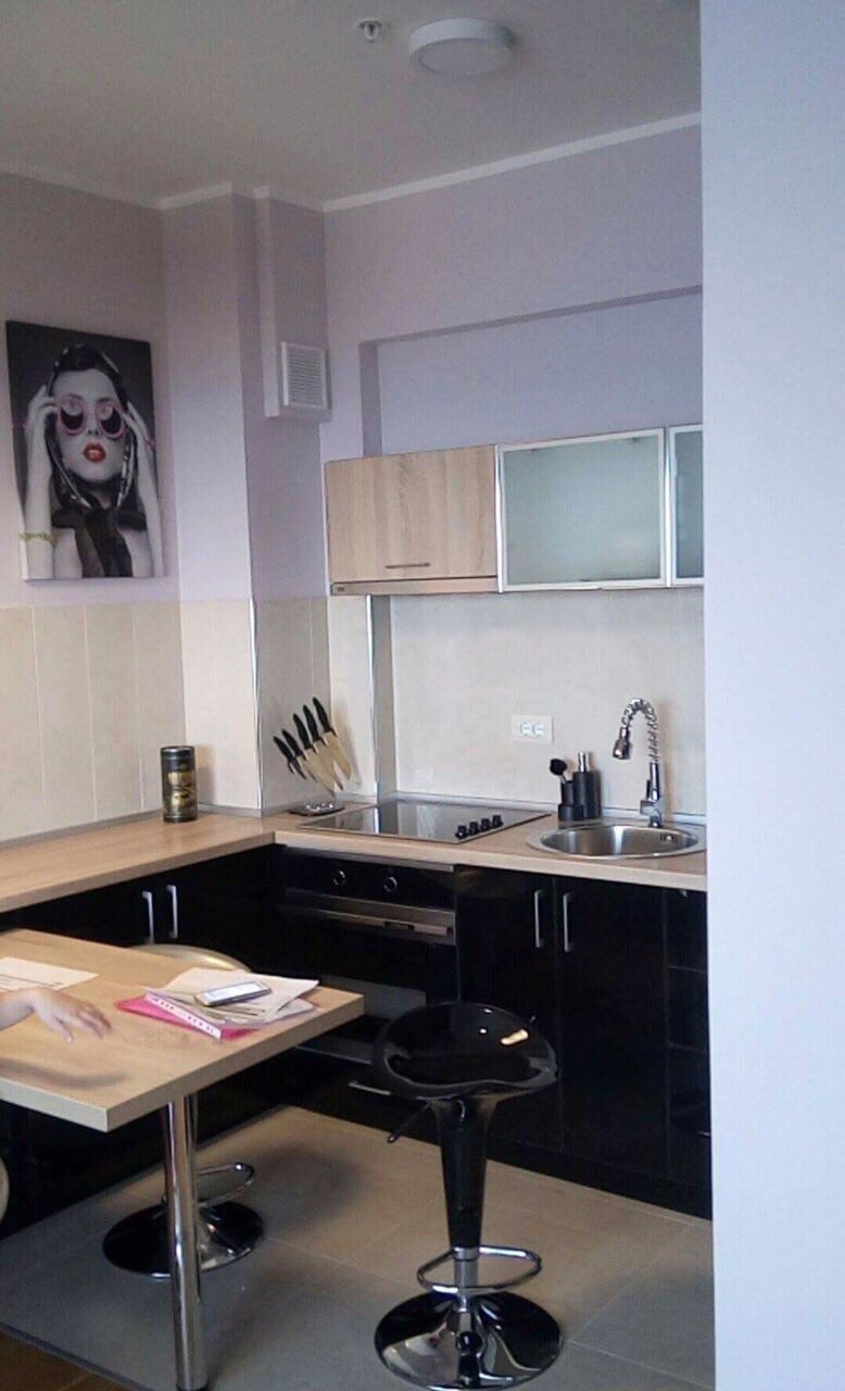 Cuisine moderne dans un appartement à Bečići, Monténégro : mobilier noir, bar et électroménager intégré.