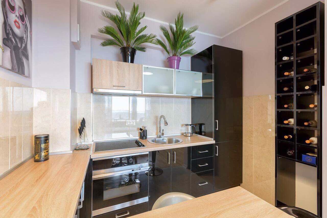 Cuisine moderne dans un appartement à Bečići, Monténégro : ensemble noir, électroménager intégré et casier à vin dans l’intérieur.