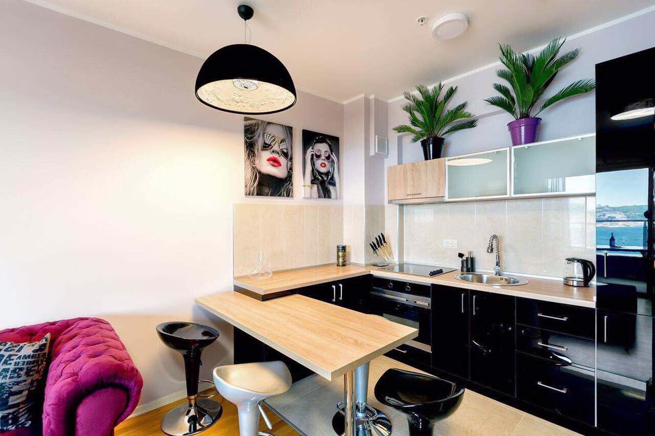 Cuisine moderne dans un appartement à Bečići, Monténégro : mobilier noir, bar et vue sur la mer depuis la fenêtre.