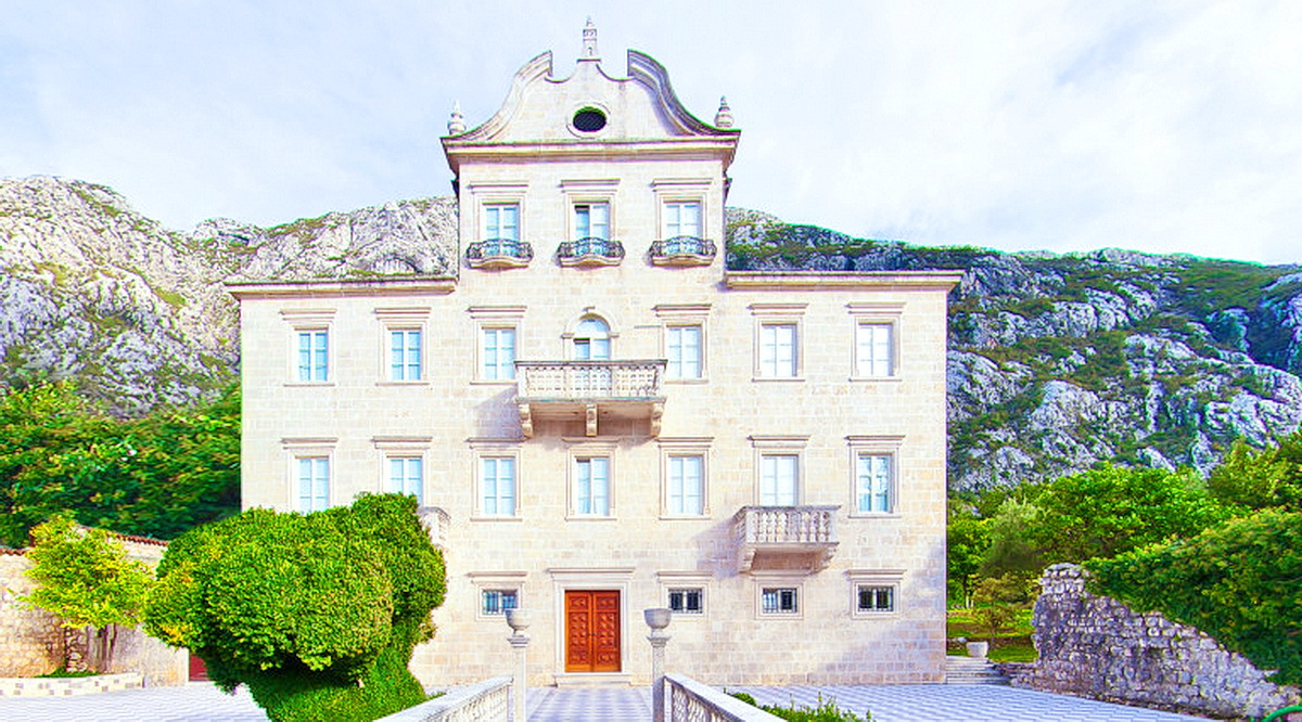 Historische Steinvilla in Dobrota, Montenegro: Gebäudefassade mit Balkonen vor Bergkulisse.