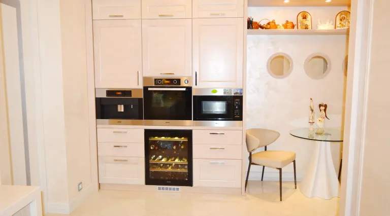Moderne Küche in einer Villa in Tivat, Montenegro: Einbaugeräte, Weinkühlschrank und Essbereich mit Glastisch.