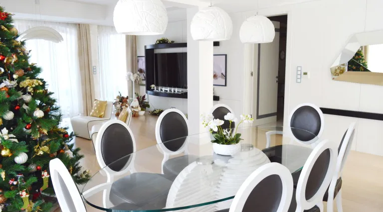 Modernes Wohnzimmer mit Essbereich in einer Villa in Tivat, Montenegro: Glastisch, Designstühle und Weihnachtsbaum.