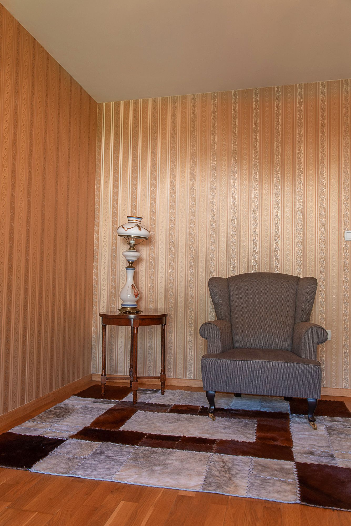 Coin cosy pour se détendre dans le salon d’une maison de ville à Lastva, Monténégro : fauteuil, lampe vintage et tapis en peaux.