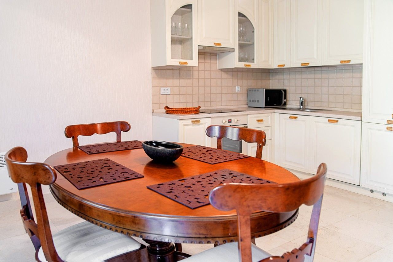 Cuisine avec meubles blancs et table à manger en bois dans une maison de ville, Lastva, Monténégro. Intérieur d’une cuisine moderne.