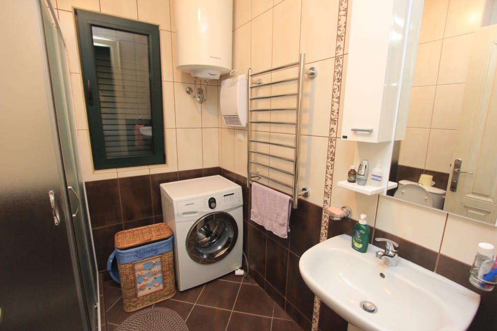 Salle de bains dans une maison de ville, Lastva, Monténégro : cabine de douche, machine à laver, chauffe-eau et revêtement en carrelage.