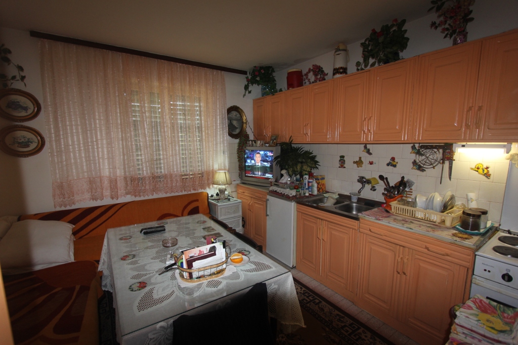 Küche mit orangefarbener Einbauküche und Essbereich in einem Haus zum Verkauf, Radovići, Montenegro. Gemütliches Interieur mit Möbeln.