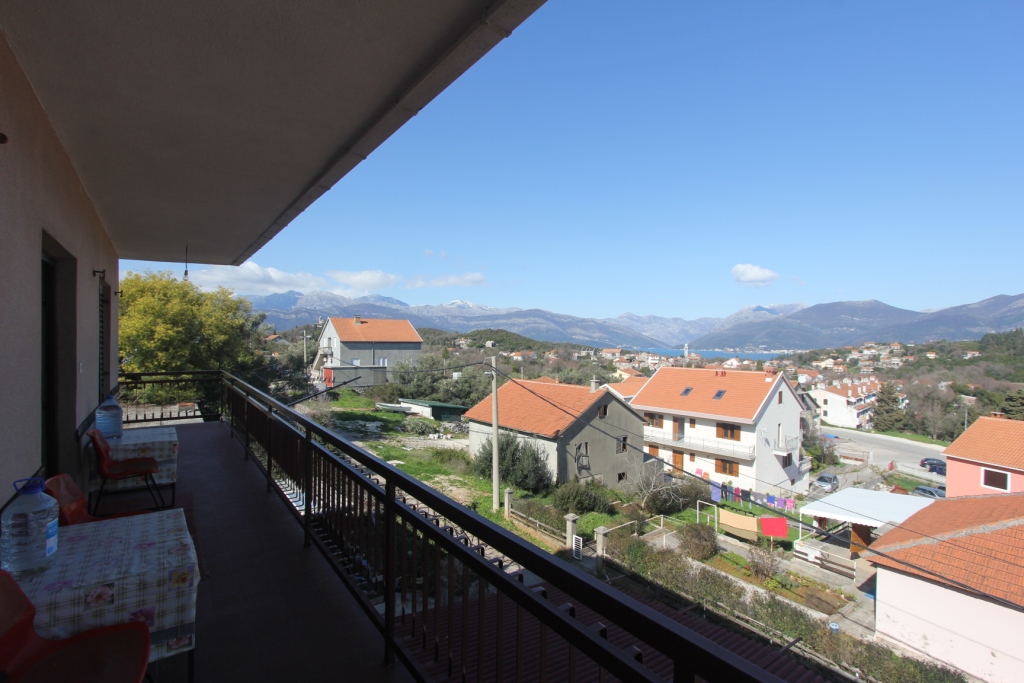 Geräumiger Balkon des Hauses in Radovici, Montenegro, mit Panoramablick auf die Berge, das Meer und die Ziegeldächer der Siedlung.