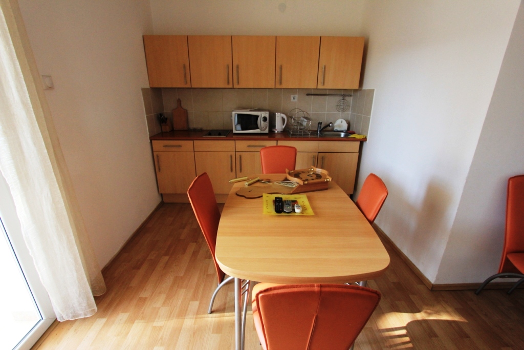 Кухня с обеденной зоной и оранжевыми стульями в мини-отеле, Сутоморе, Черногория. Светлый интерьер с деревянной мебелью.