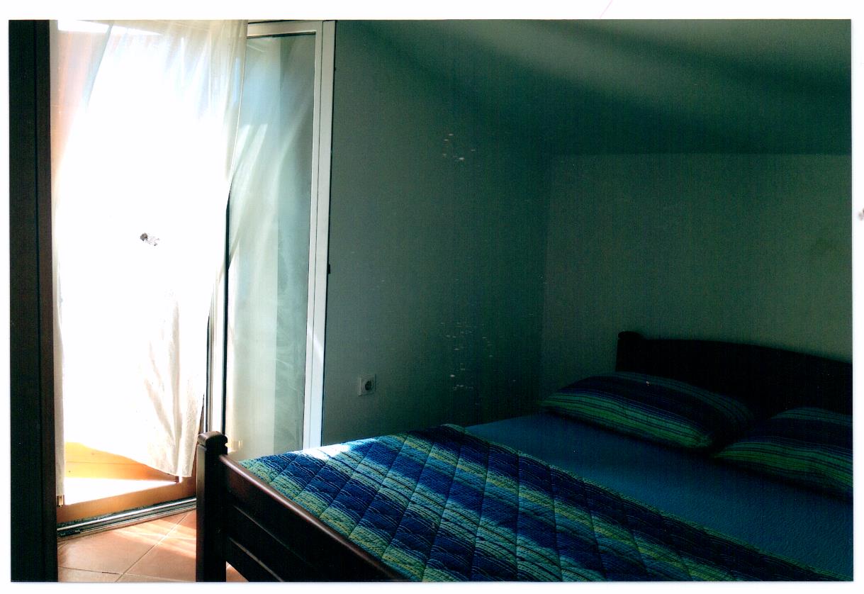 Schlafzimmer mit Doppelbett und Zugang zum Balkon in einer Villa auf Luštica, Montenegro. Helles Interieur, Blick auf die Terrasse.