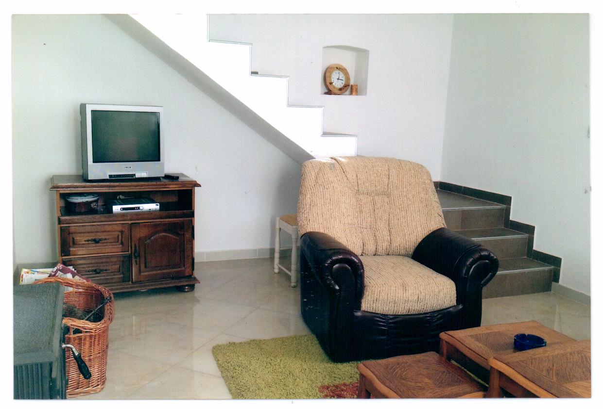 Wohnzimmer mit Sessel und Treppe in einer Villa in Luštica, Montenegro: Innenraum mit Holzmöbeln und TV-Bereich.