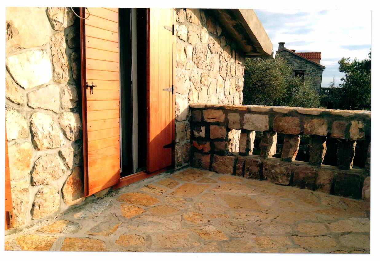Steinbalkon einer Villa in Luštica, Montenegro: Terrasse mit Natursteinverkleidung und Holzläden.