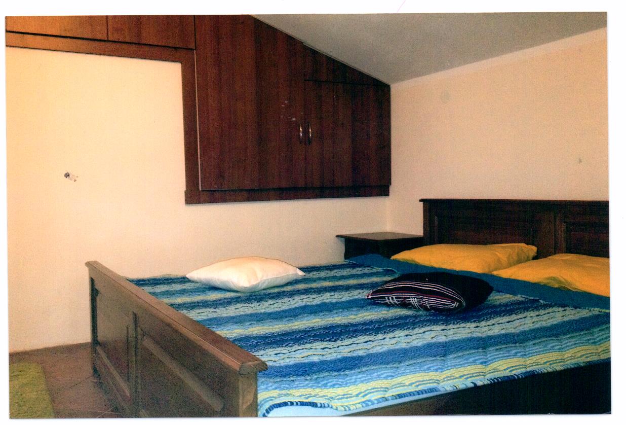 Schlafzimmer mit Doppelbett und Einbauschrank in einer Villa in Luštica, Montenegro. Gemütliches Dachgeschoss-Interieur.