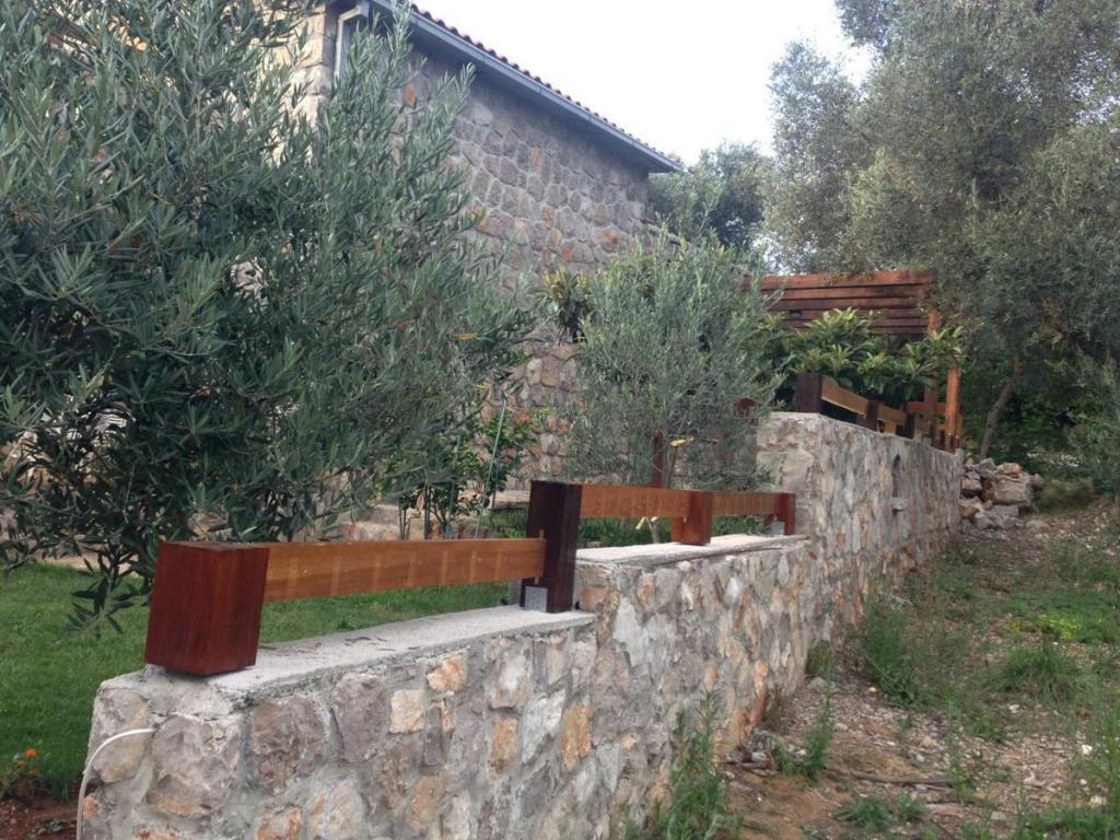 Steinvilla in Luštica, Montenegro: Fassade aus Naturstein, Holzgeländer und Olivenhain auf dem Grundstück.