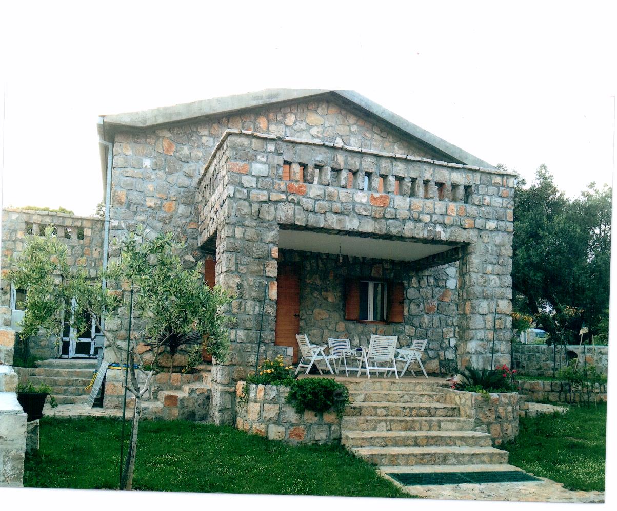 Steinvilla in Luštica, Montenegro: Fassade aus Naturstein, Terrasse mit Gartenmöbeln und grüner Garten.