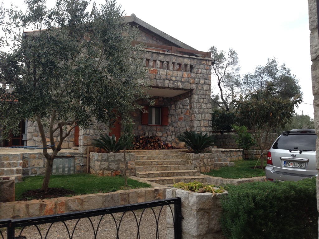 Zweistöckige Villa aus Naturstein mit Terrasse und Garten in Luštica, Montenegro. Hausfassade mit Steinmauerwerk.