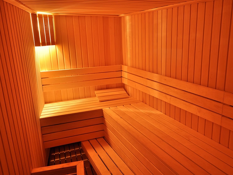 Moderne Holzsauna im Hotel Petrovac, Montenegro: Innenraum der Sauna mit Bänken und warmer Beleuchtung.