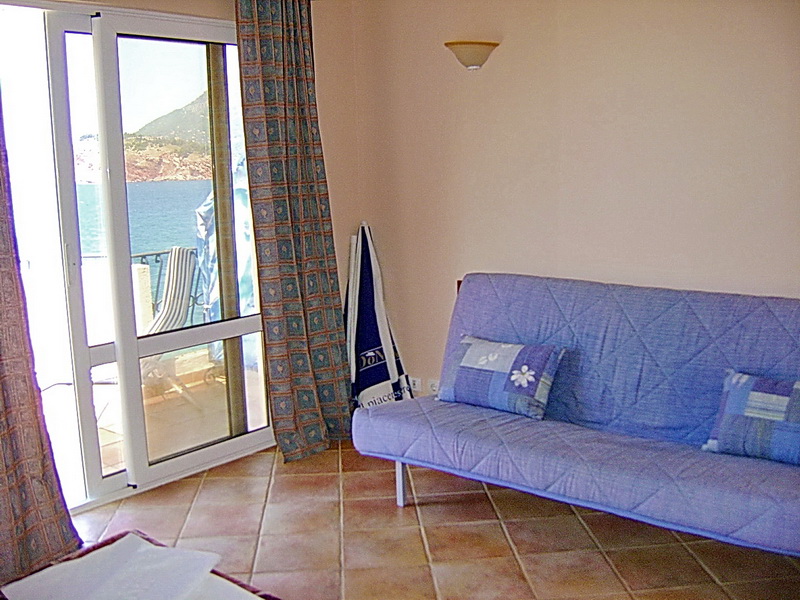 Wohnzimmer im Hotel in Sutomore, Montenegro: blaues Sofa, Fliesenboden und Panoramablick auf das Meer von der Terrasse.