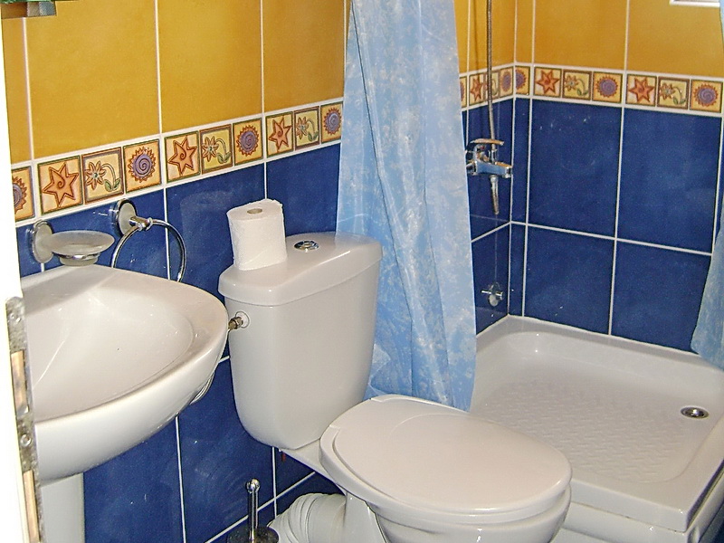 Badezimmer im Hotel in Sutomore, Montenegro: Duschkabine, Sanitäranlagen und helle Fliesen mit Blumenornament.