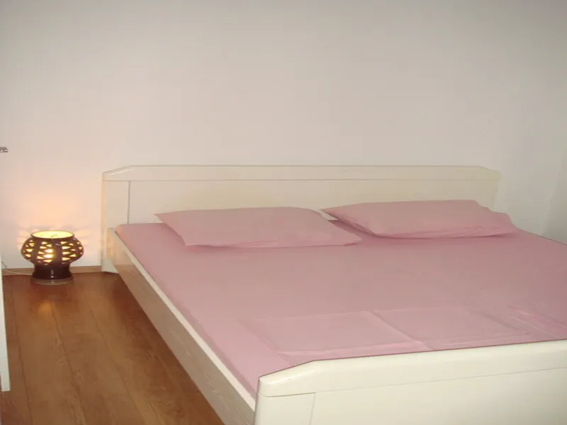 A wide shot of a bedroom with a double bed and a lit lamp.
