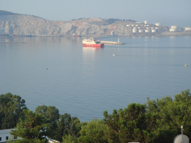 Weitwinkelaufnahme eines ruhigen Meeres mit Schiff und Bergen.