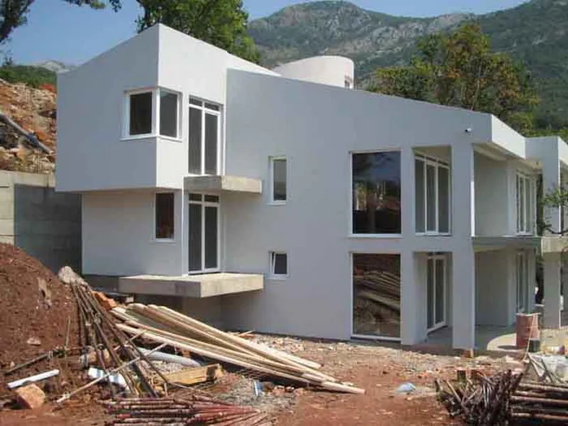 Modernes Haus im Bau mit hellem Fassade und Balkonen in hügeliger Gegend