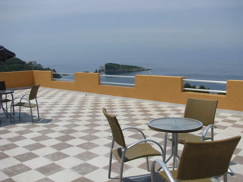 Terrace with wicker tables and sea view in a house, Uteha, Montenegro. Checkerboard tile on the balcony.