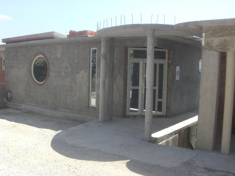 Im Bau befindliches Haus in Šušanj, Montenegro: Fassade mit rundem Fenster, Betonstützen und eingebauten Fenstern.