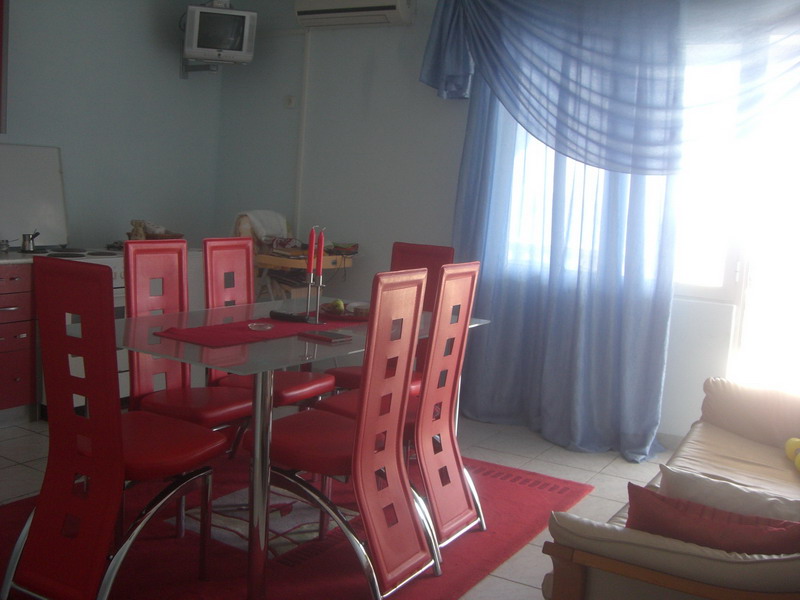Wohnzimmer mit Essbereich im Haus, Shushan, Montenegro: Glastisch, rote Stühle und helle Vorhänge.