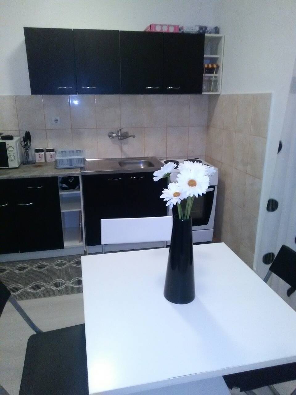 Küche mit schwarzer Einbauküche und Esstisch im Haus, Shushan, Montenegro. Modernes Interieur mit weißer Ausstattung.