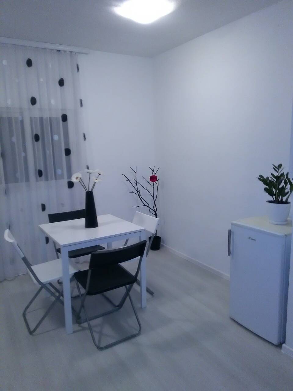 Helle Küche in einem Haus in Šušanj, Montenegro: Essbereich mit weißem Tisch, Stühlen und Kühlschrank im Innenraum.