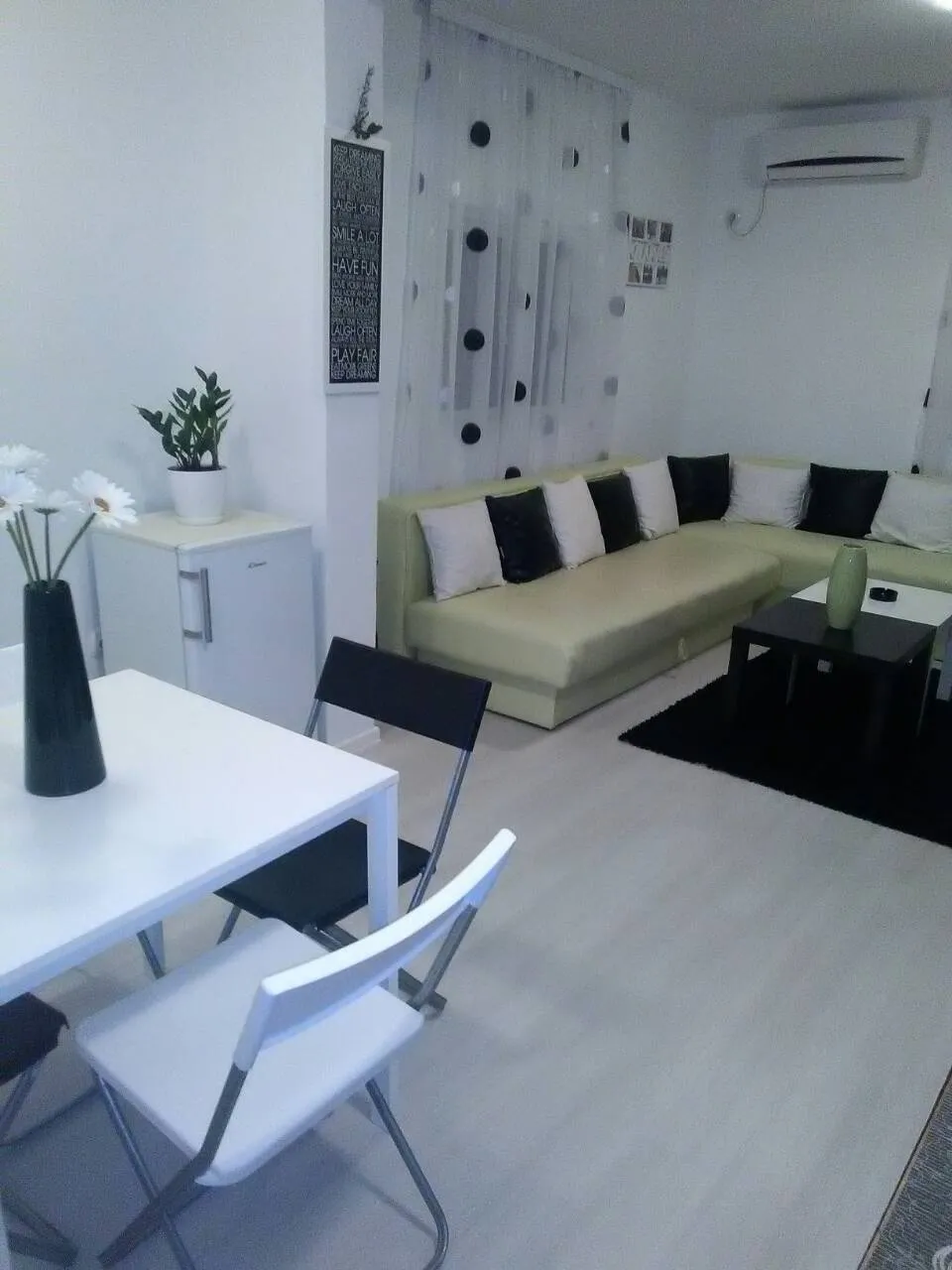 Wohnzimmer mit grüner Ecksofa, Esstisch und moderner Dekoration.