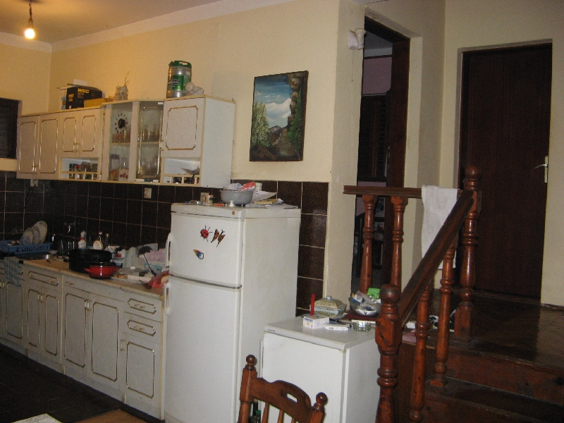 Küche in einem Haus in Šušanj, Montenegro: helle Einbauküche, dunkler Fliesenspiegel, Kühlschrank und Holztreppe ins zweite Obergeschoss.