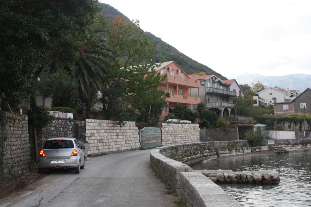 Pogled na priobalni put, kamene ograde i stambene kuće u naselju Stoliv, Crna Gora.