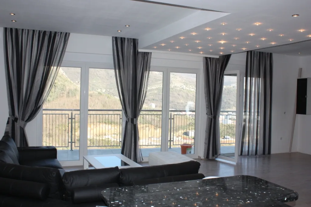 Geräumiges Wohnzimmer mit schwarzem Sofa und Panoramafenstern.