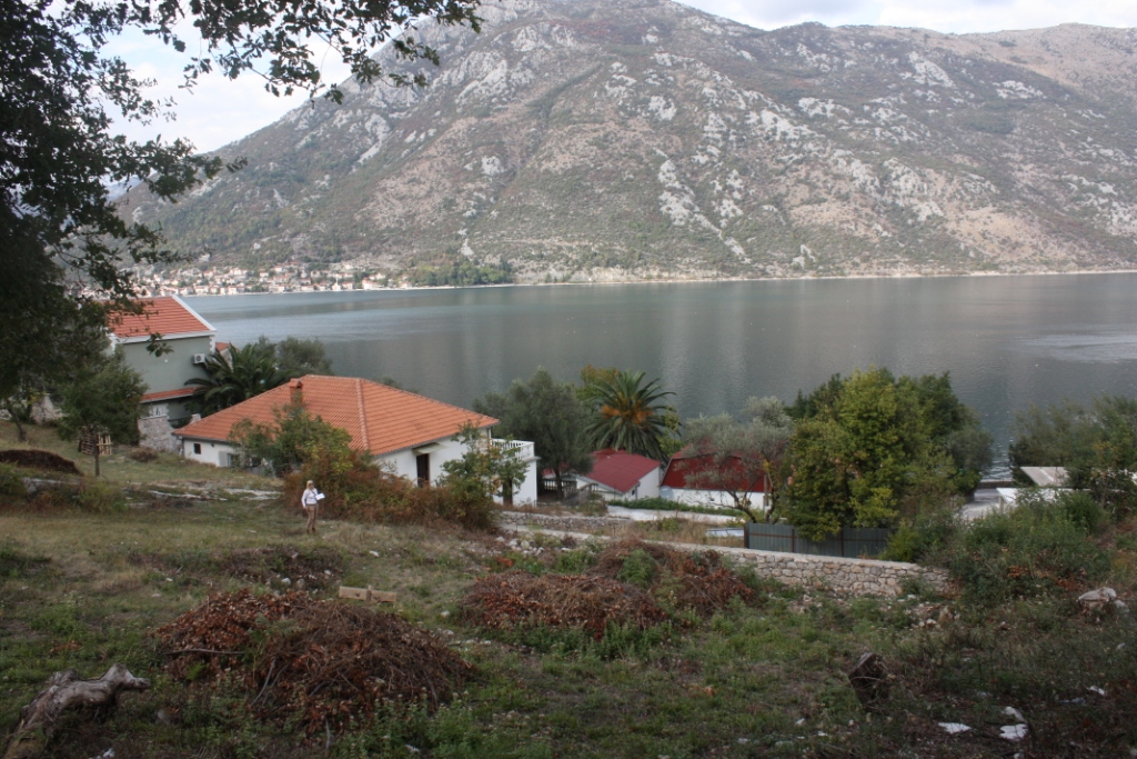 Građevinsko zemljište u Stolivu, Crna Gora, sa panoramskim pogledom na Bokokotorski zaliv i planine, u blizini stambenih kuća.