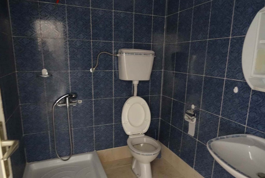 Badezimmer mit blauen Fliesen, Duschwanne und Sanitäranlagen in einem Haus zum Verkauf in Bigovo, Montenegro.