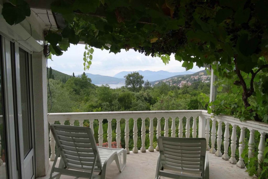 Terrasse mit Liegestühlen und Blick auf das Meer und die Berge in einem Haus in Bigovo, Montenegro, mit Weinreben bewachsen und mit Balustrade.